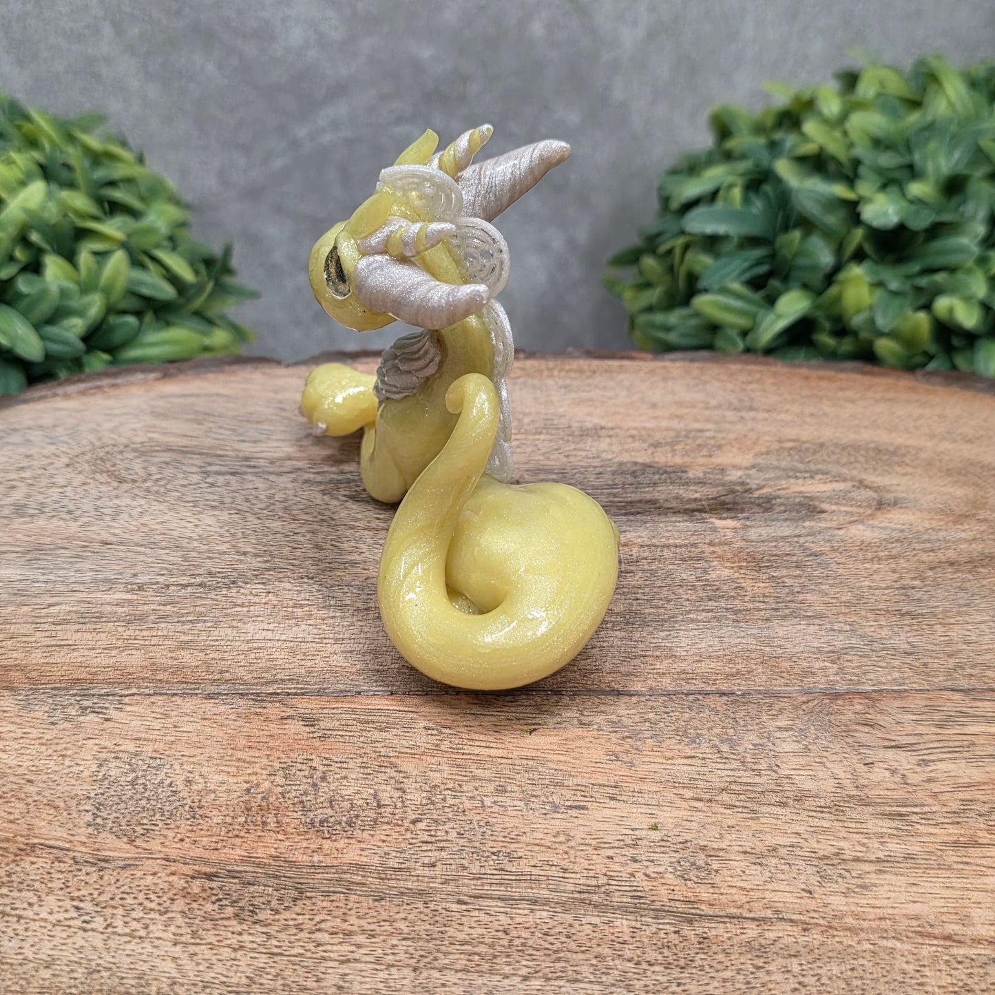 A dragon sculpture on wood surface with greenery