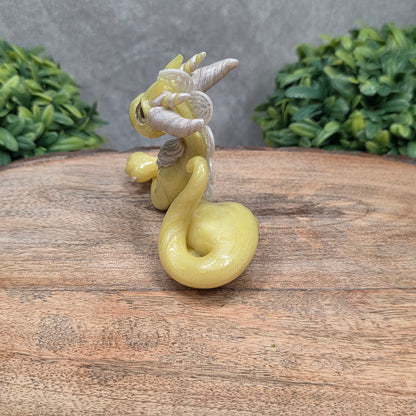 A dragon sculpture on wood surface with greenery