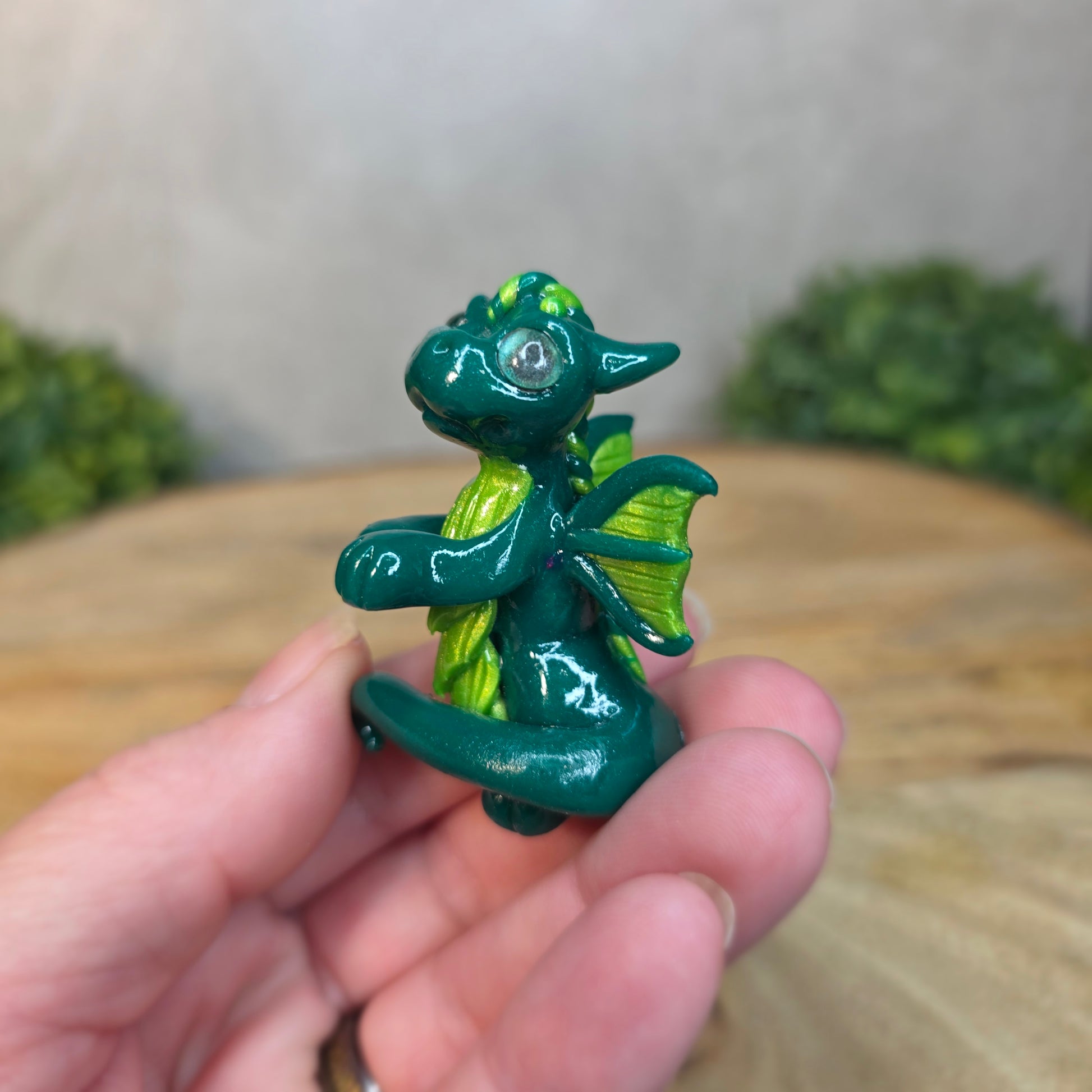A small green dragon against a blurred wood background
