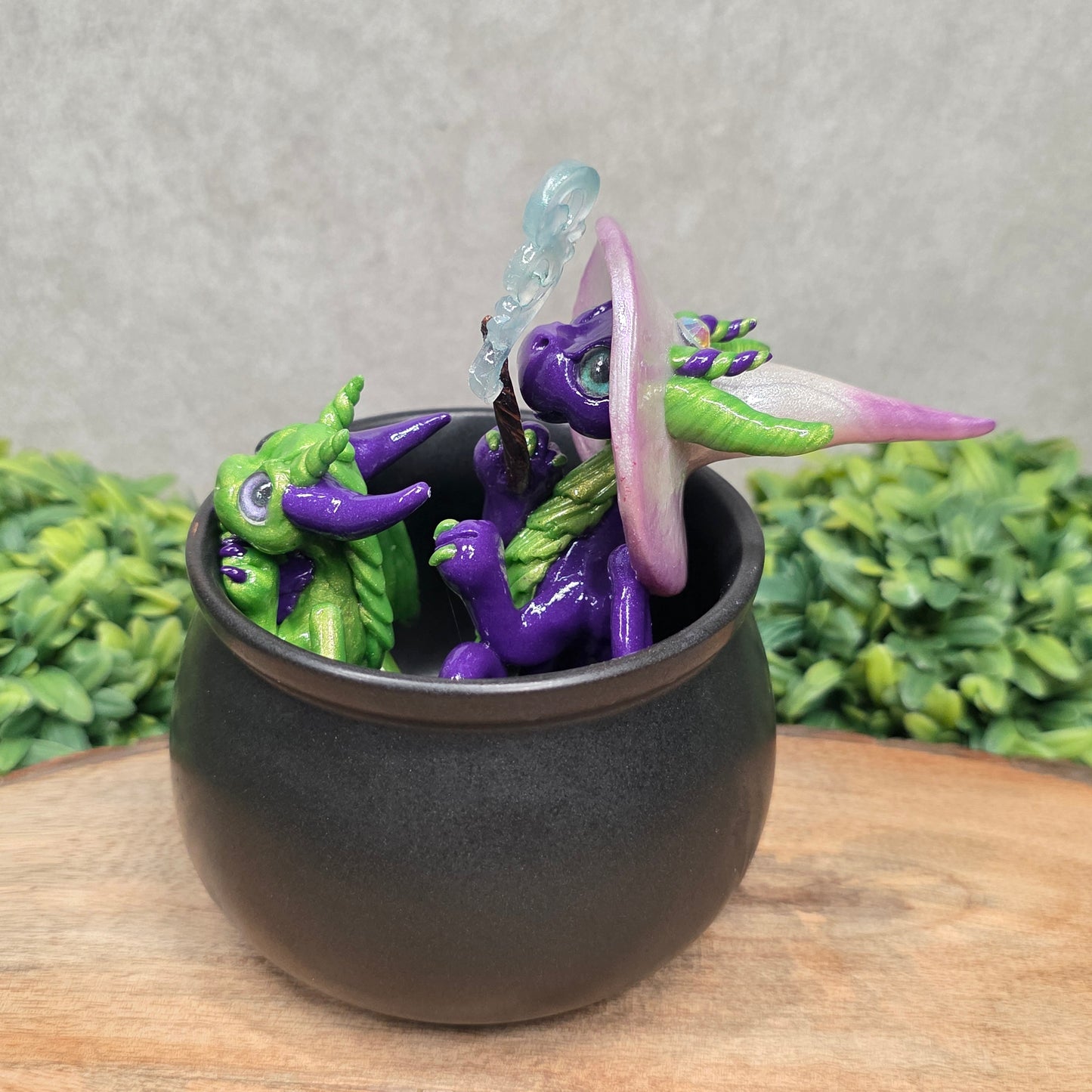 A pair of clay dragons in a cauldron with greenery