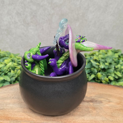 A pair of clay dragons in a cauldron with greenery