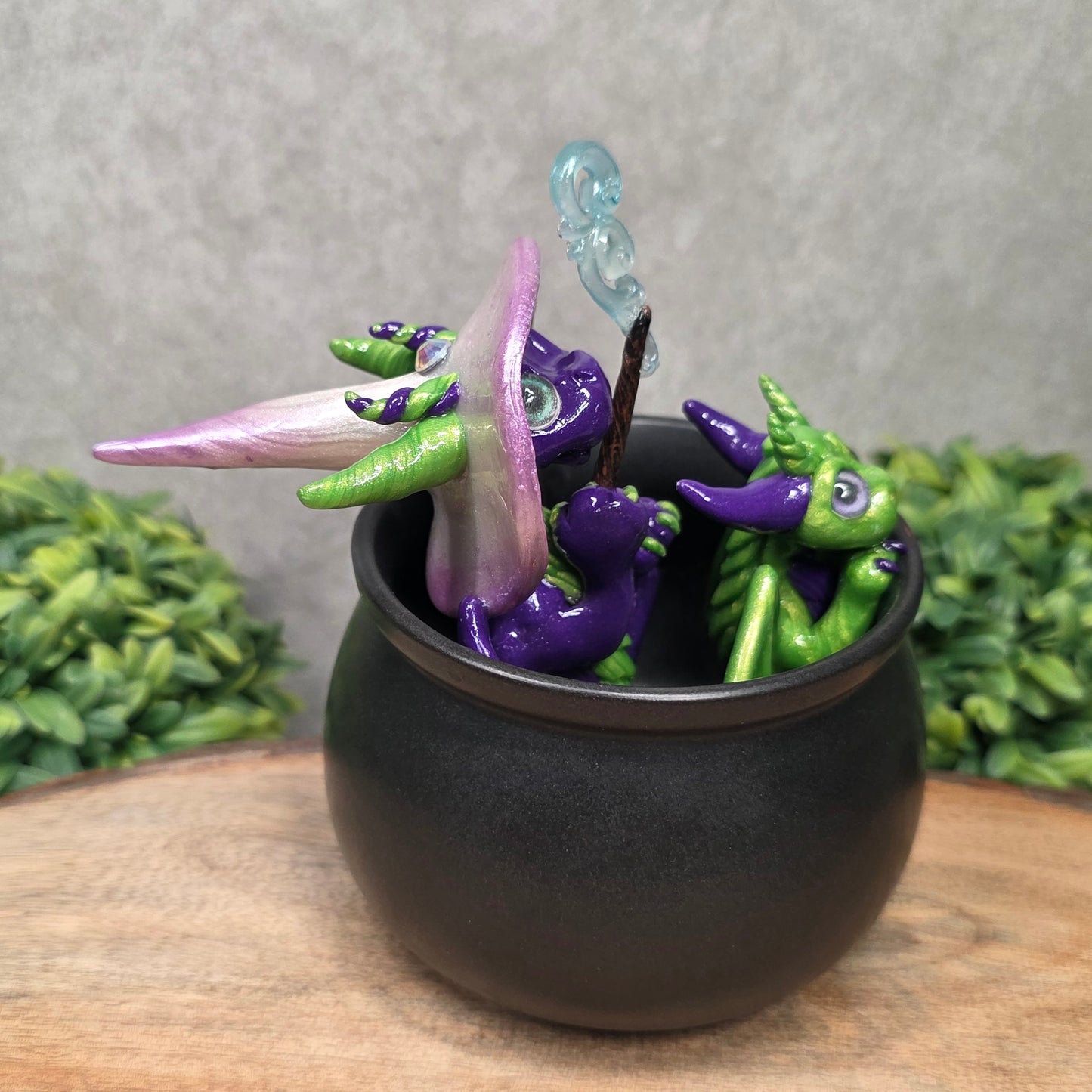 A pair of clay dragons in a cauldron with greenery