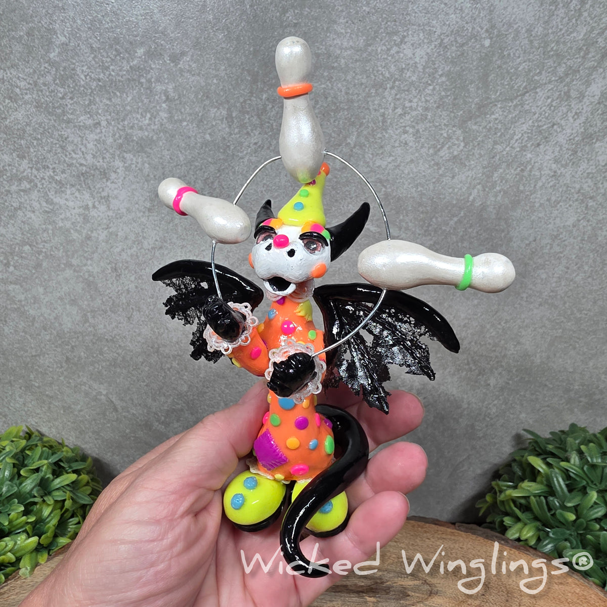A clown dragon juggling on a wood surface with greenery