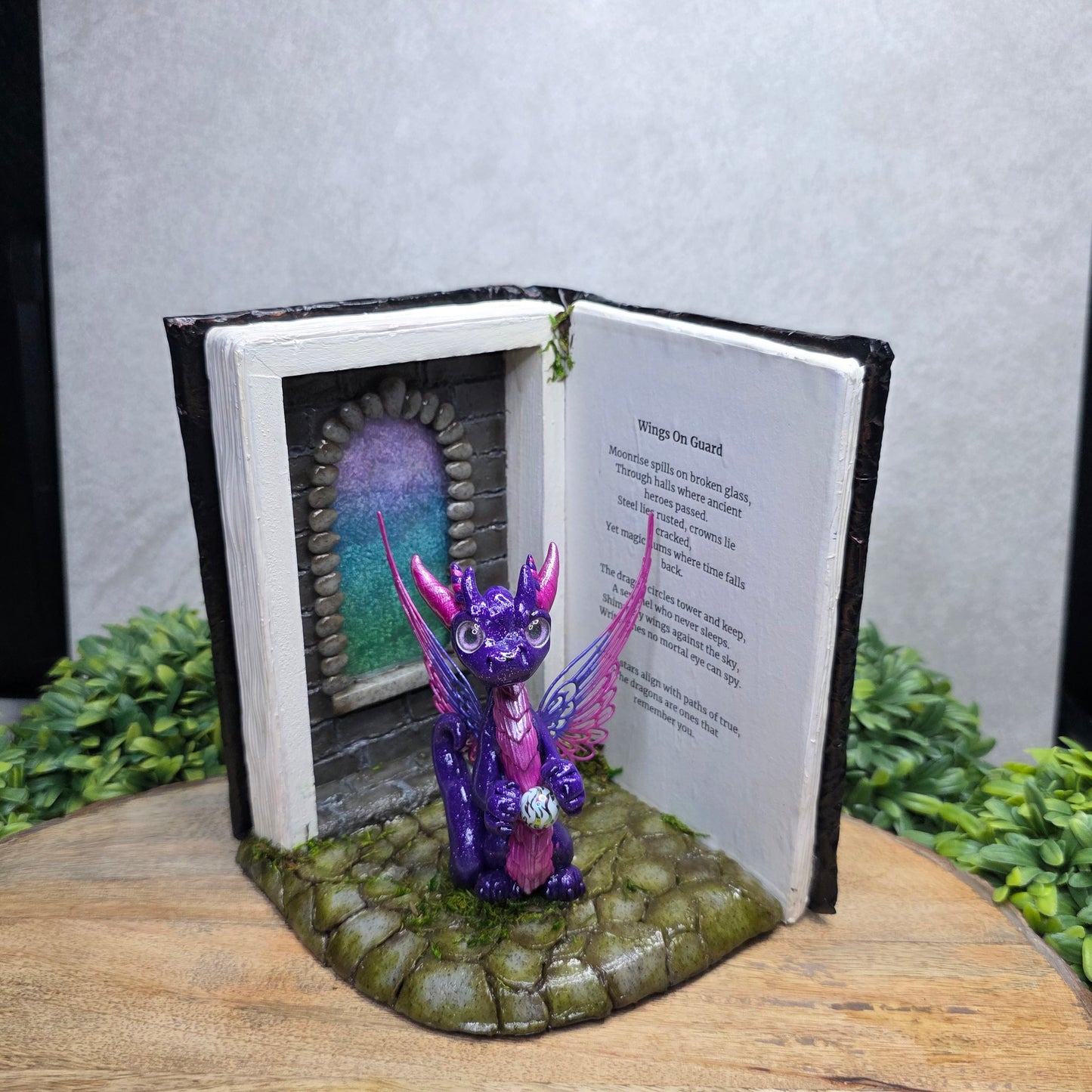 Book nook with fairy dragon on a wood surface with greenery