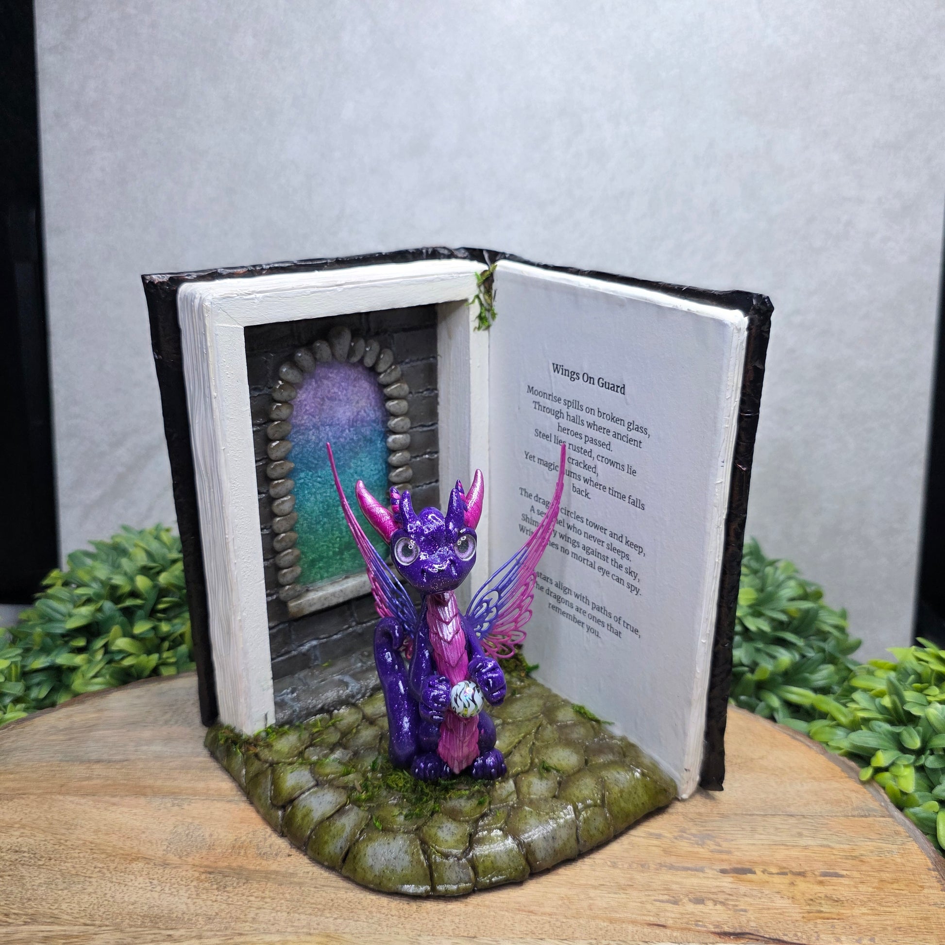 Book nook with fairy dragon on a wood surface with greenery