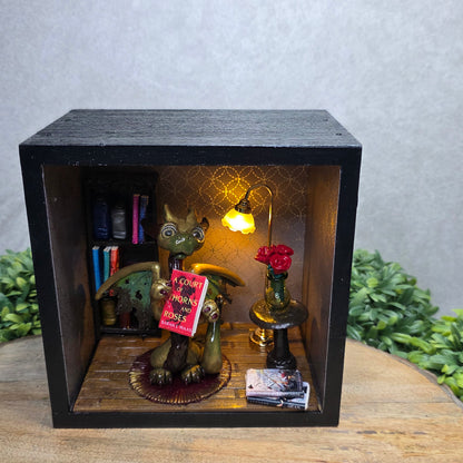 Book nook with dragon on a wood surface with greenery