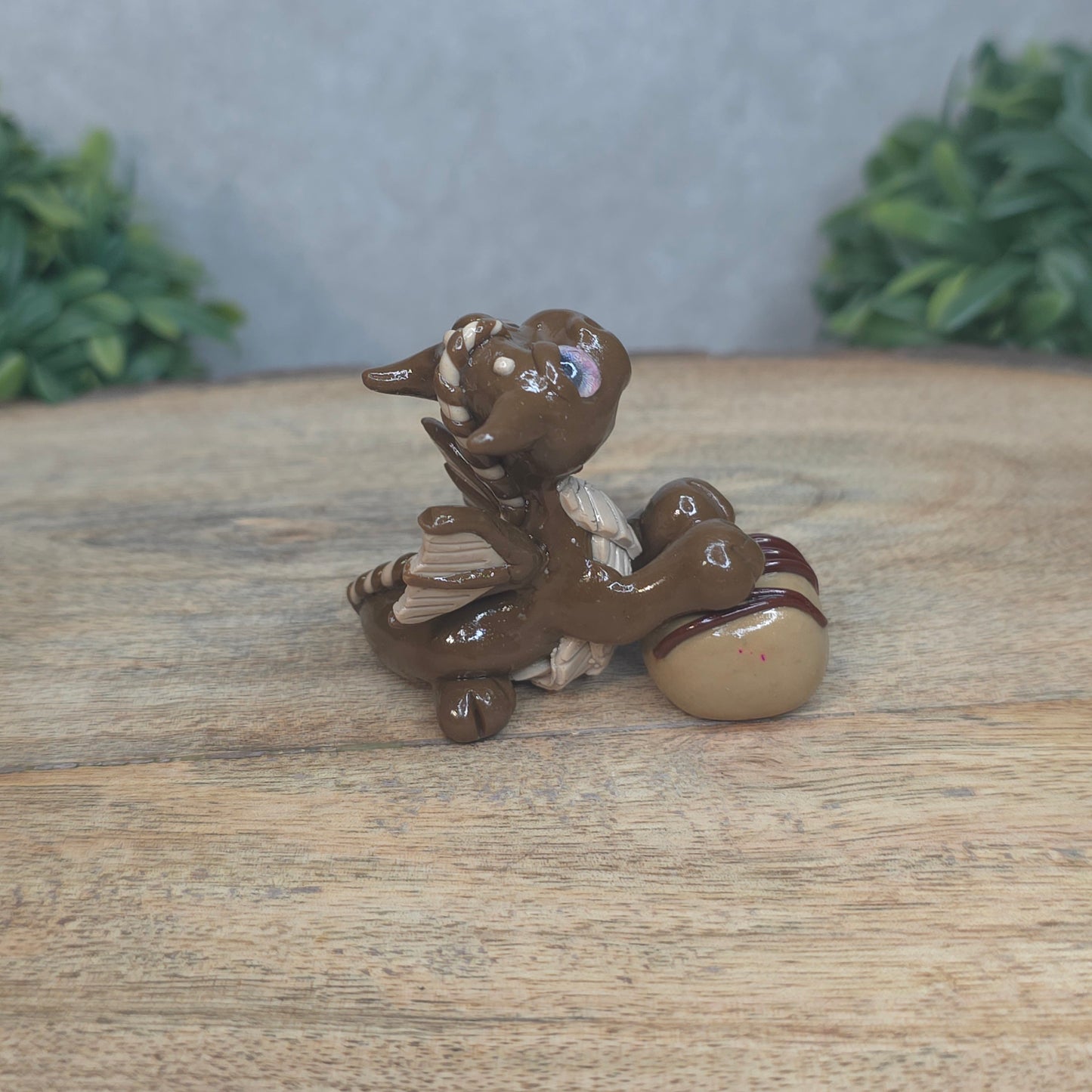 A baby polymer clay dragon with a chocolate truffle against a blurred background