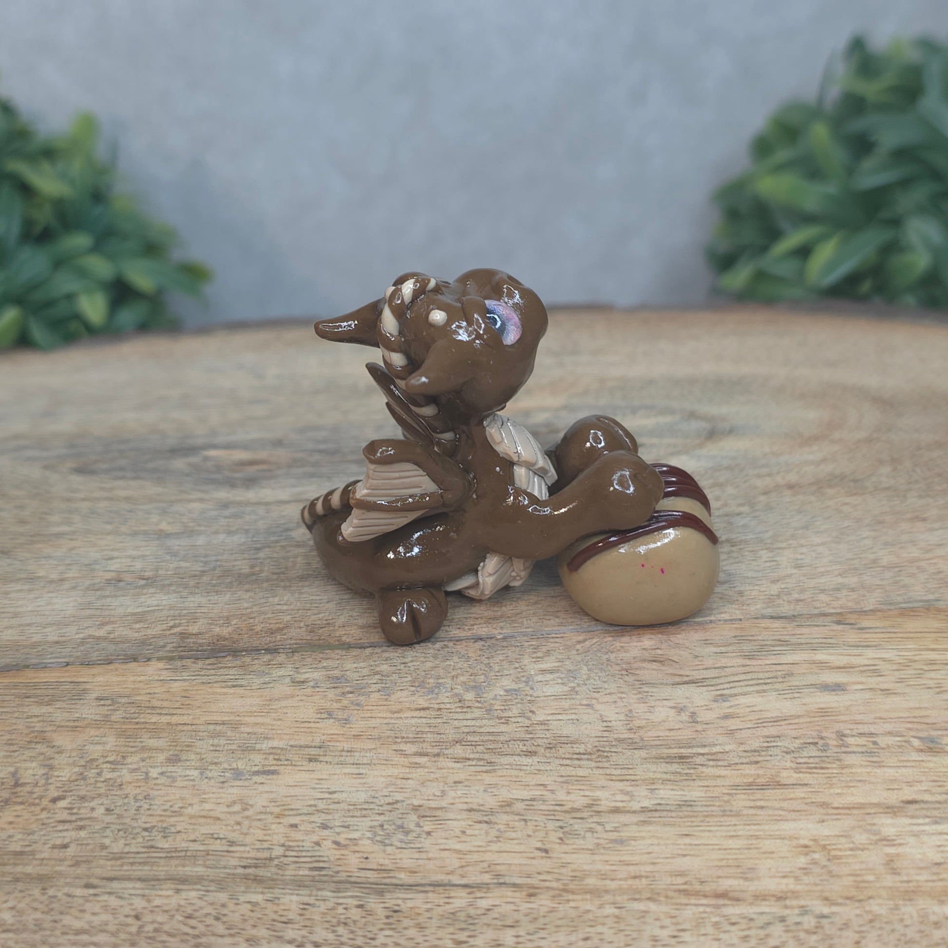 A baby polymer clay dragon with a chocolate truffle against a blurred background