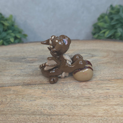 A baby polymer clay dragon with a chocolate truffle against a blurred background