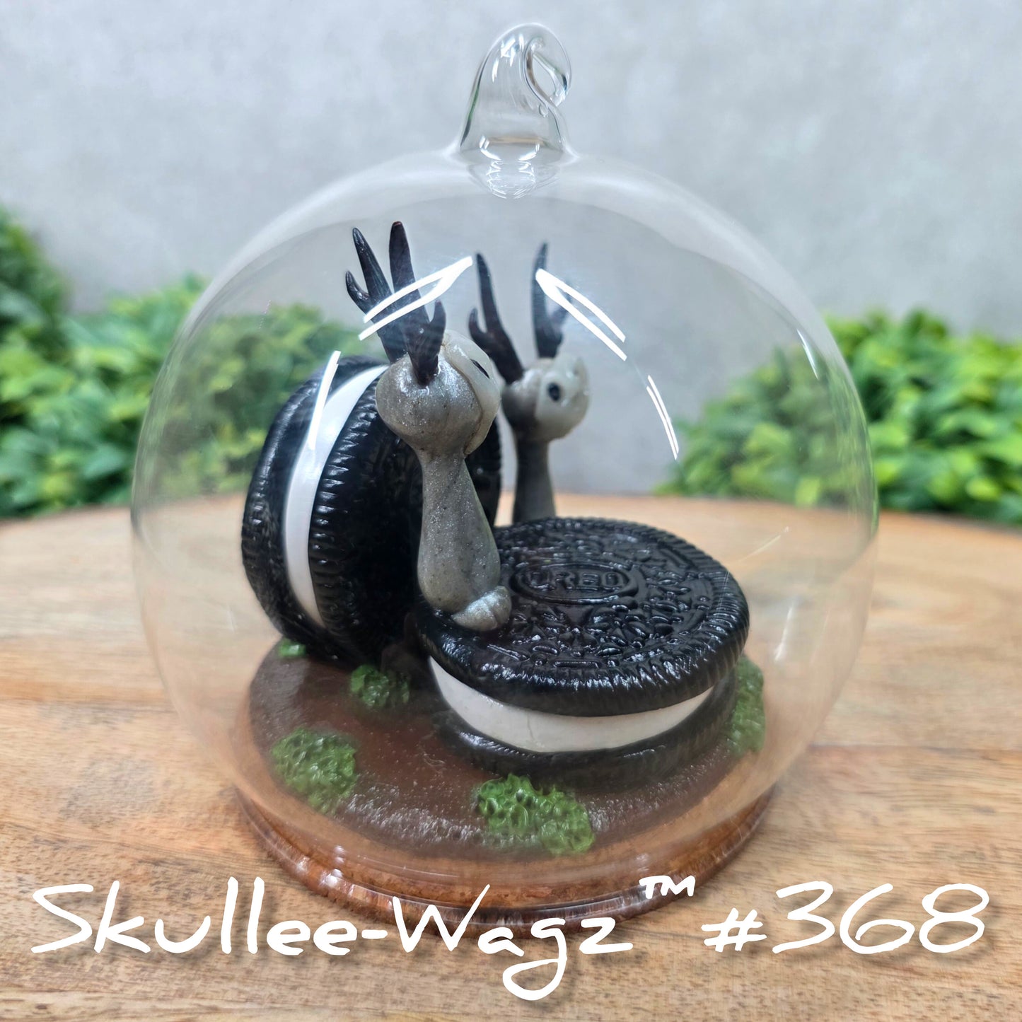 Two Skullee-Wagz with cookies in a  glass dome set on a wood surface with greenery. Text reads Skullee-Wagz #368