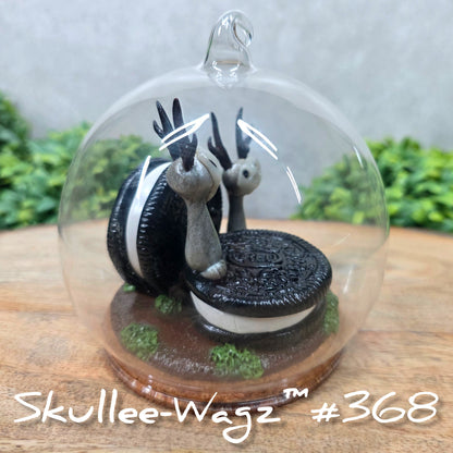 Two Skullee-Wagz with cookies in a  glass dome set on a wood surface with greenery. Text reads Skullee-Wagz #368