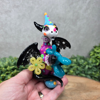 A clown dragon with balloon animals on wood surface with greenery