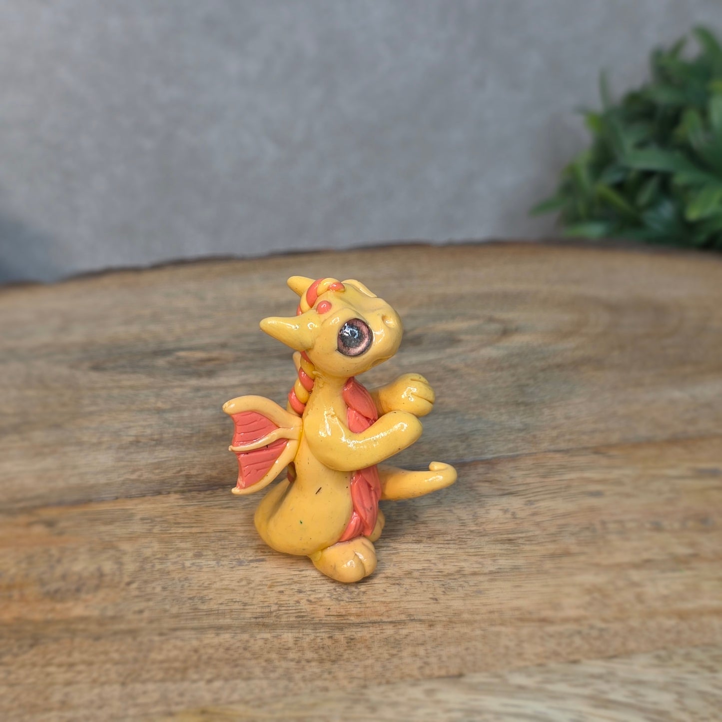 A small peach dragon against a blurred wood background