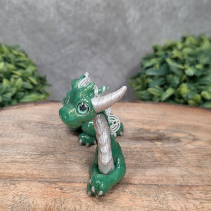 A dragon sculpture on wood surface with greenery