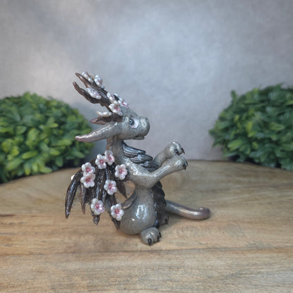 A gray colored dragon with cherry blossom accents