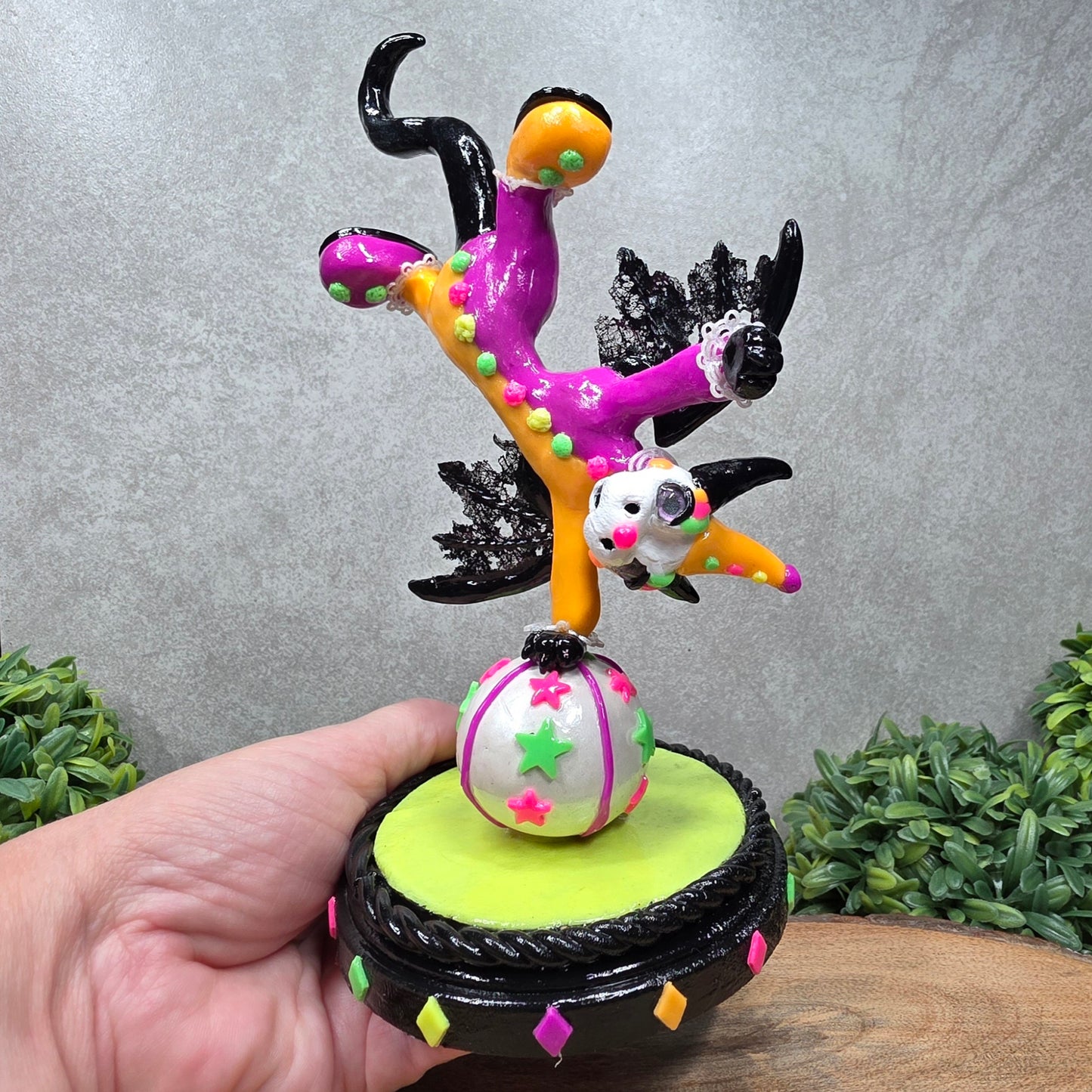 A clown dragon balancing on a ball on a wood surface with greenery
