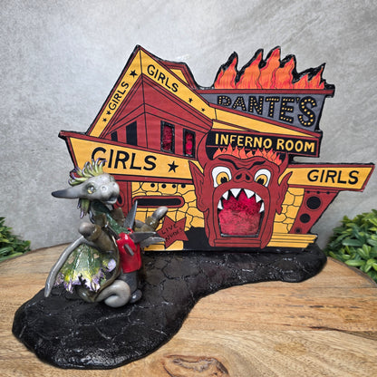 A clay dragon standing against an Inferno Room backdrop on a wood surface with greenery.