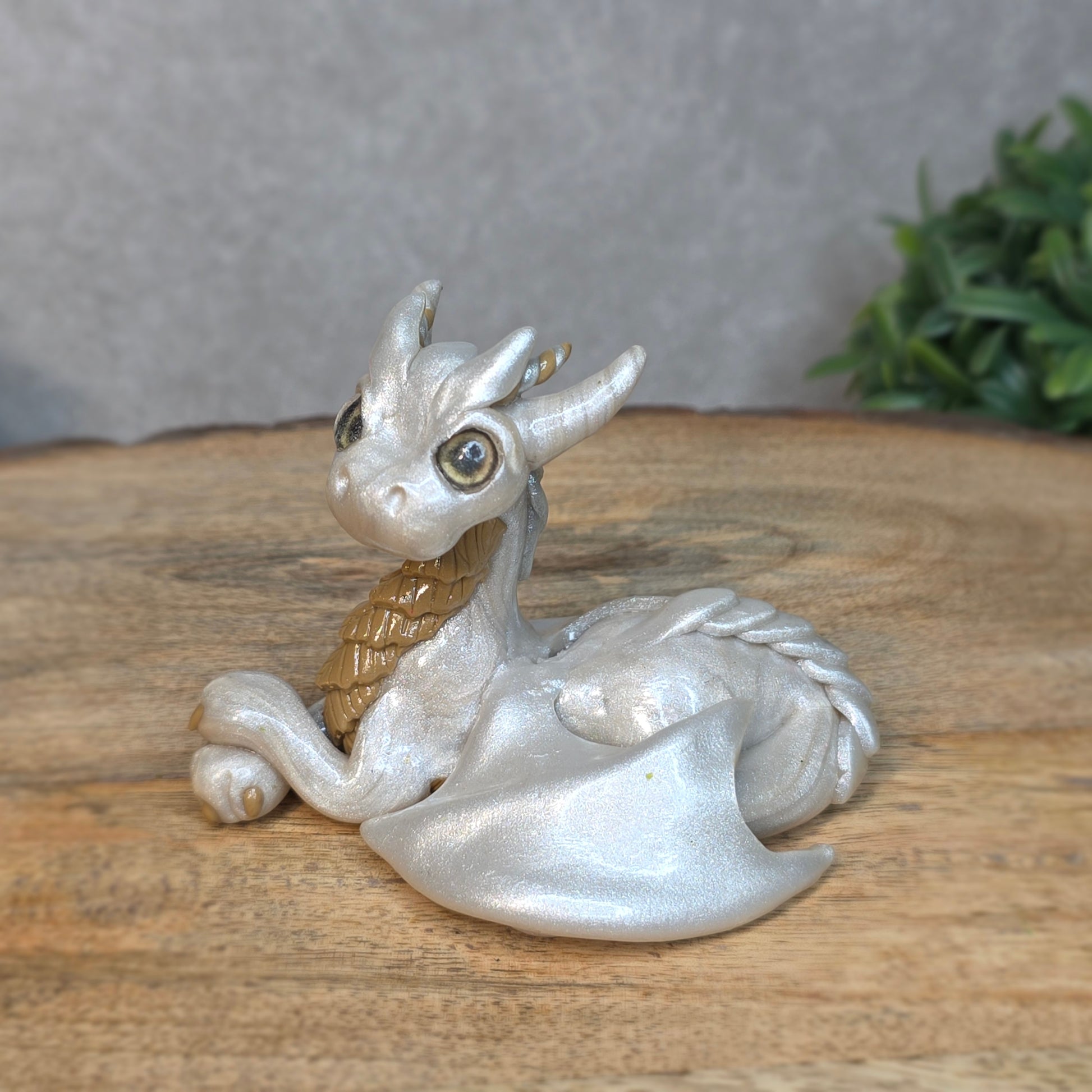 A pearl and tan clay dragon against a blurred wood surface