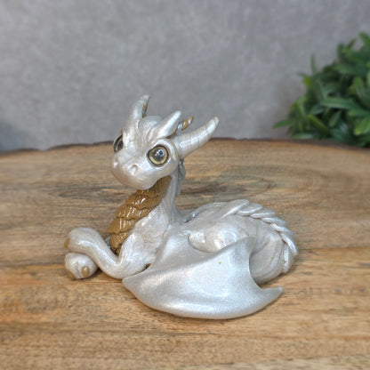 A pearl and tan clay dragon against a blurred wood surface