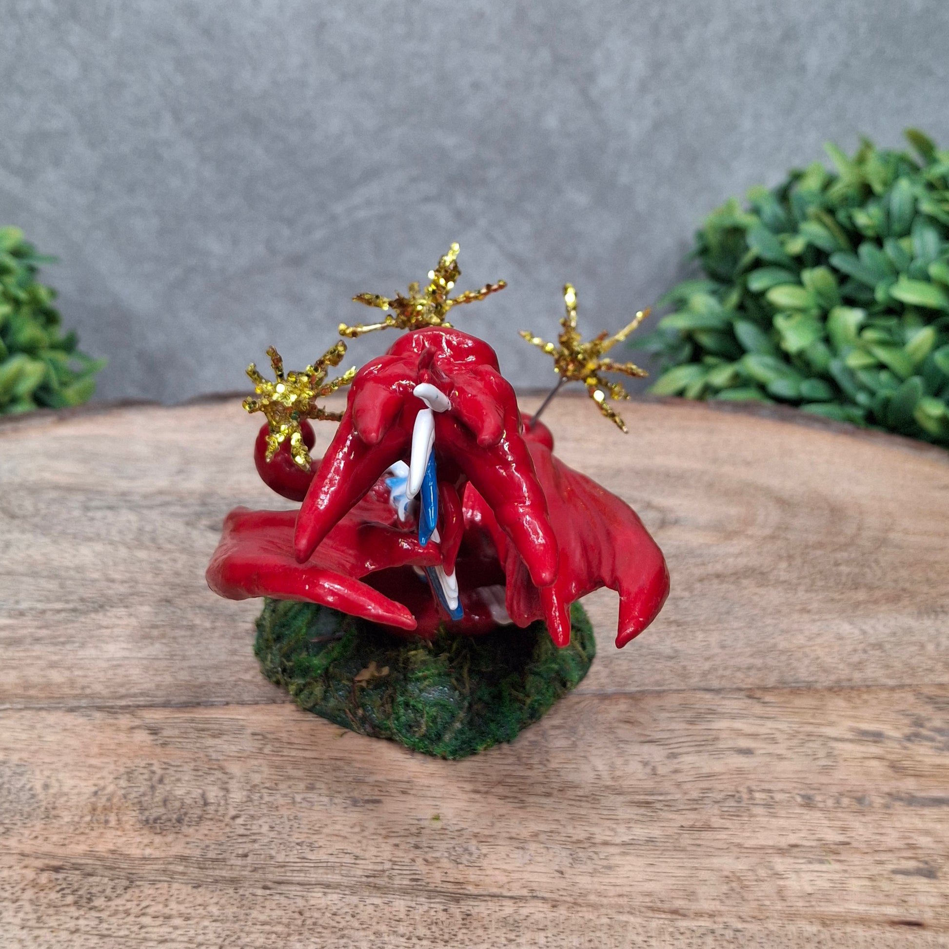 A clay dragon with sparklers against a wood surface with greenery