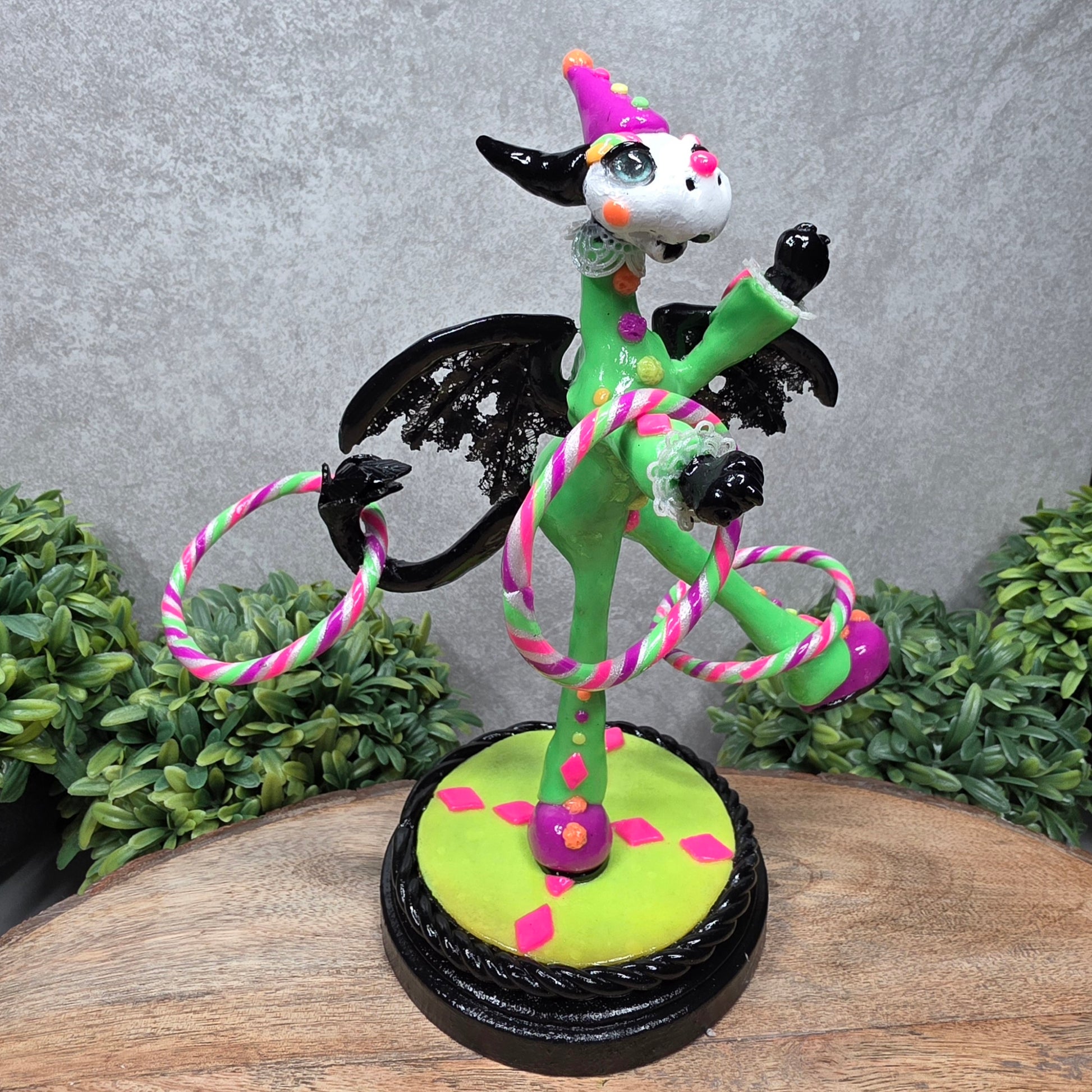 A clown dragon with hoola hoops on a wood surface with greenery
