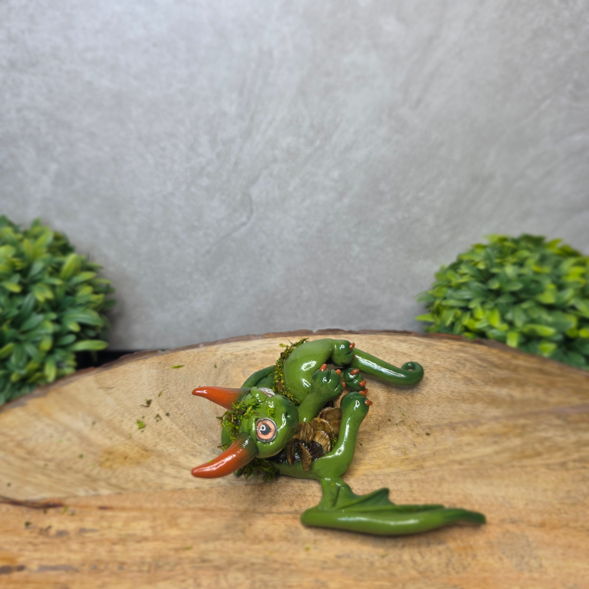 A green clay dragon against a blurred background