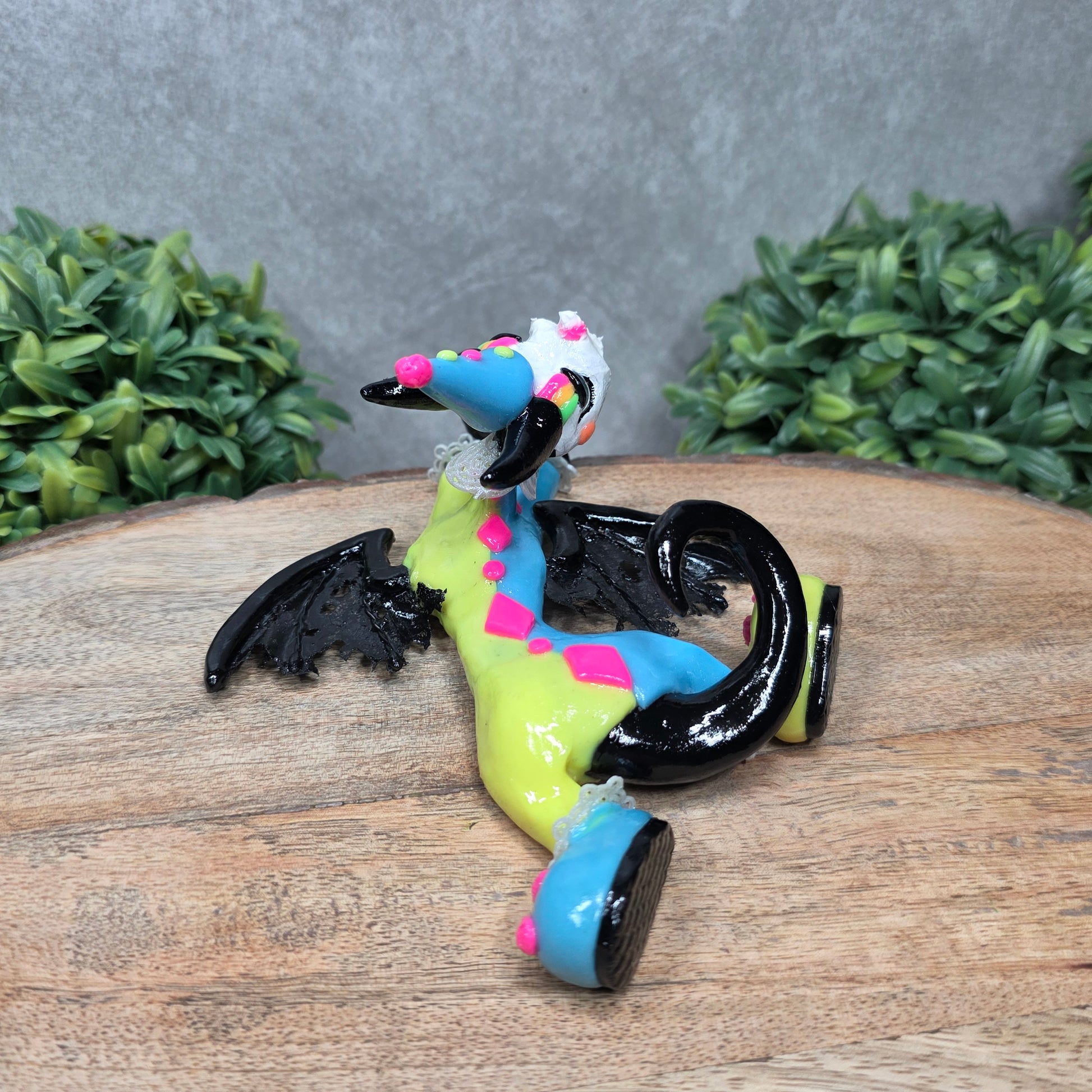 A clown dragon with cream pie on face on wood surface with greenery