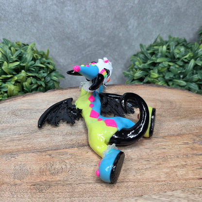 A clown dragon with cream pie on face on wood surface with greenery