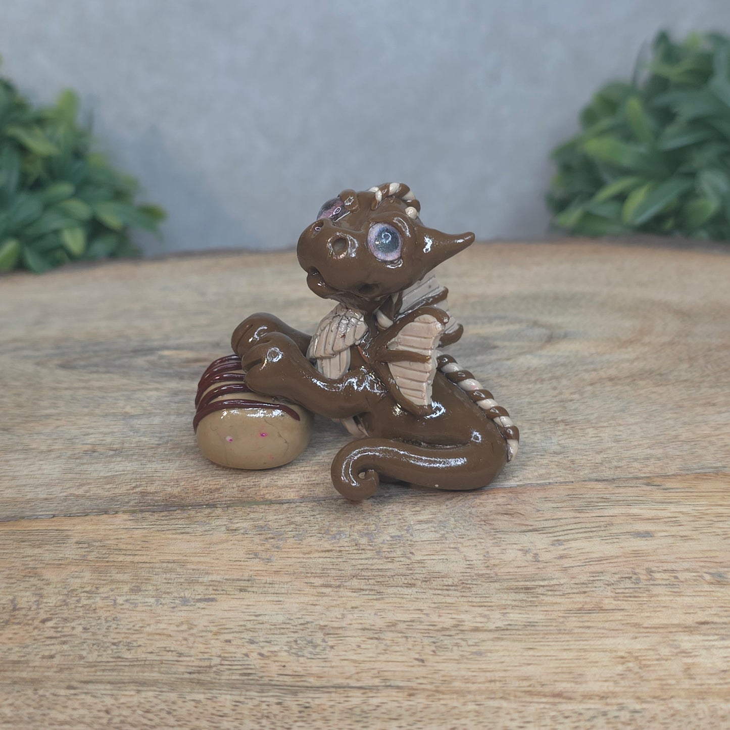 A baby polymer clay dragon with a chocolate truffle against a blurred background