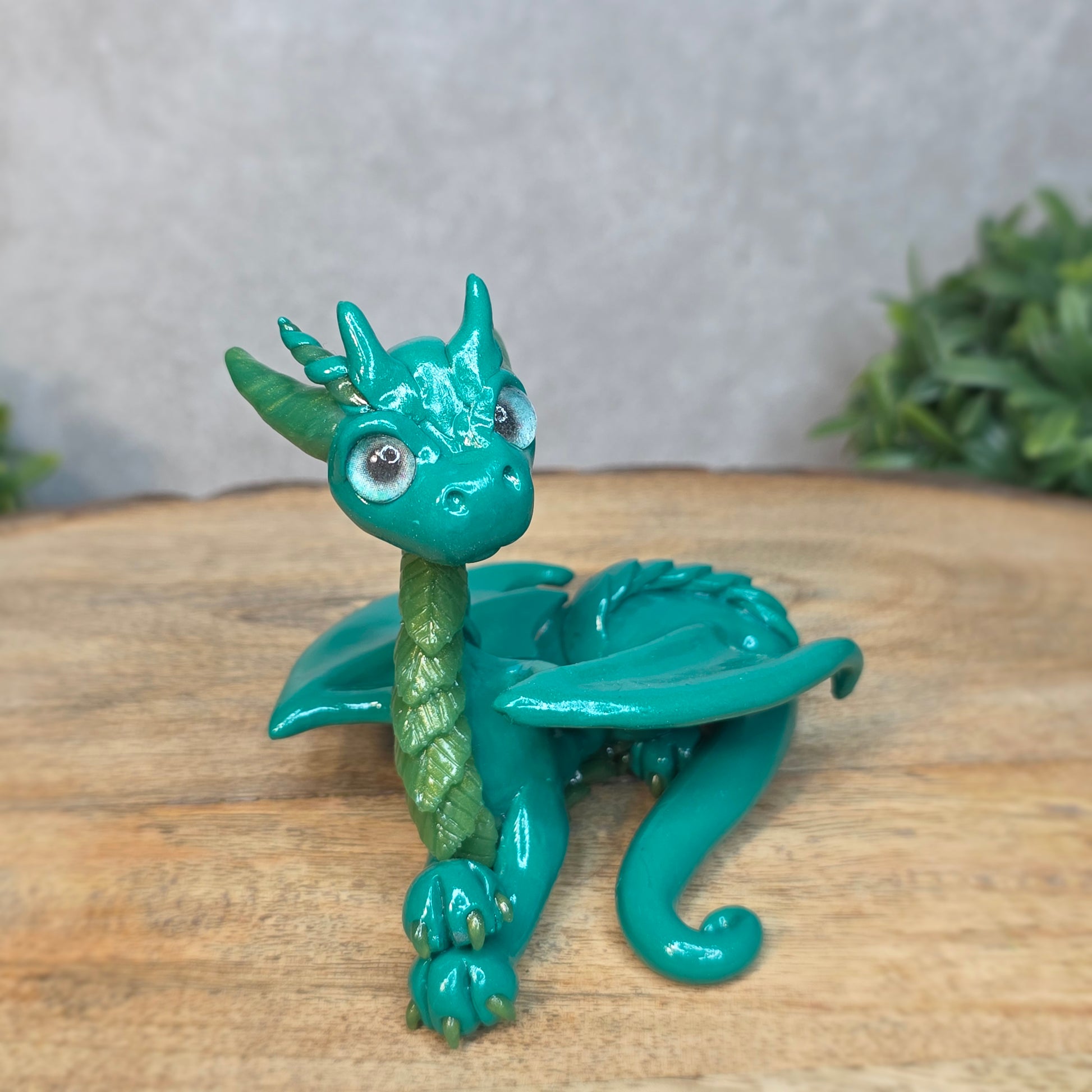 A green clay dragon against a blurred wood surface