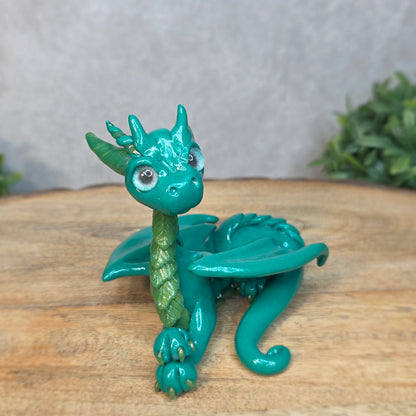 A green clay dragon against a blurred wood surface