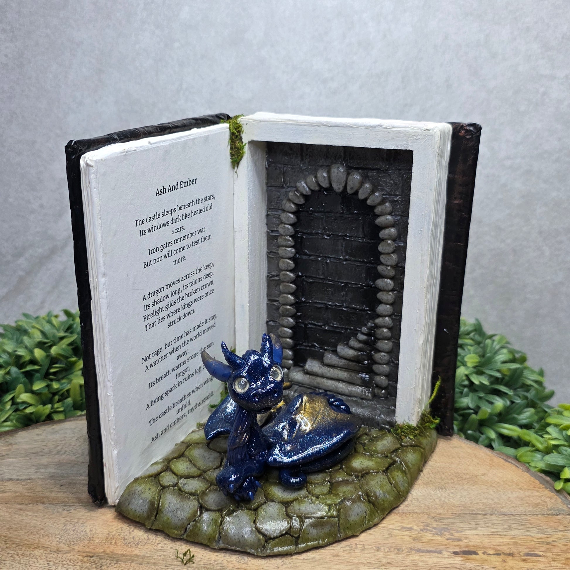 Book nook with dragon on a wood surface with greenery