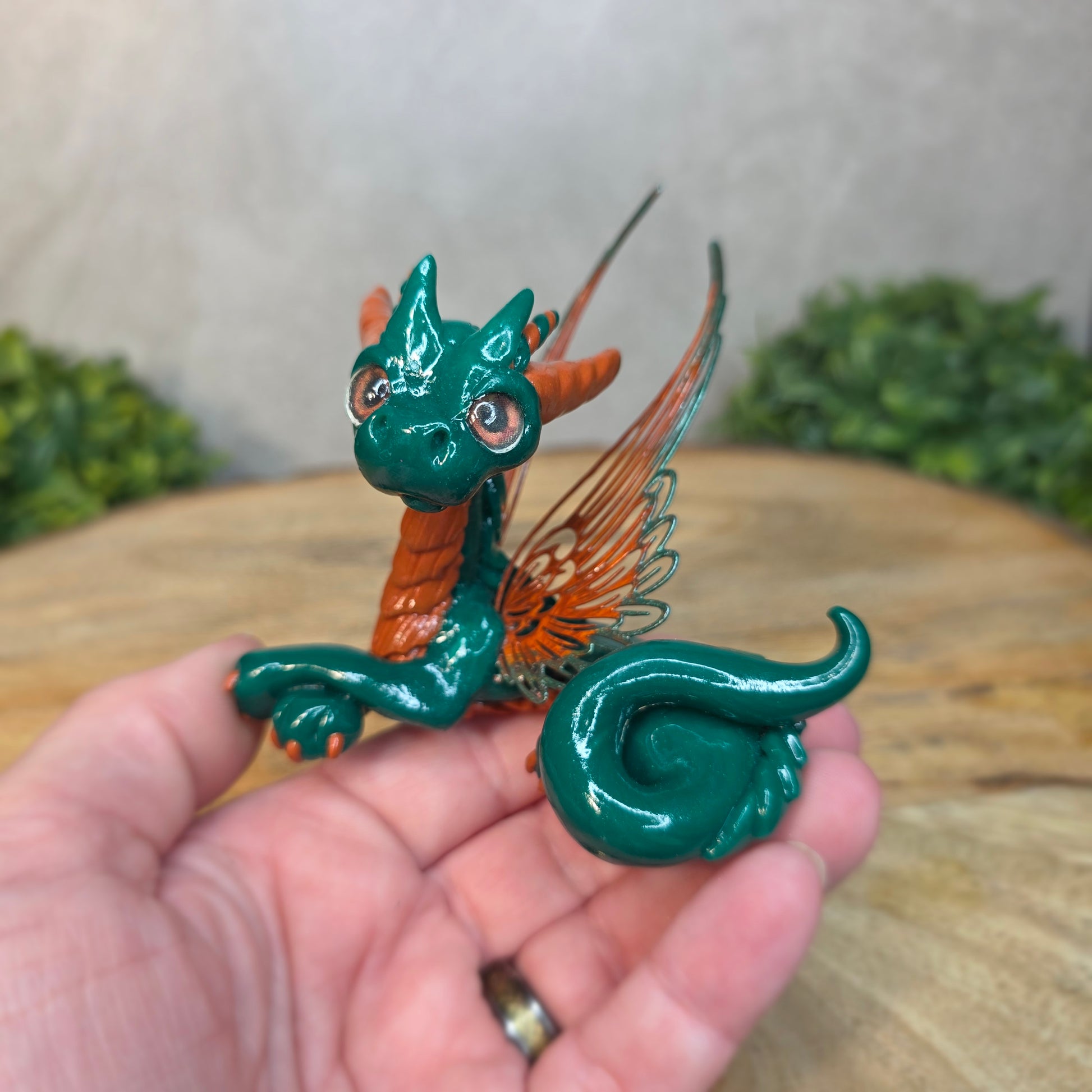Hand holding a small green dragon figurine with a blurred background