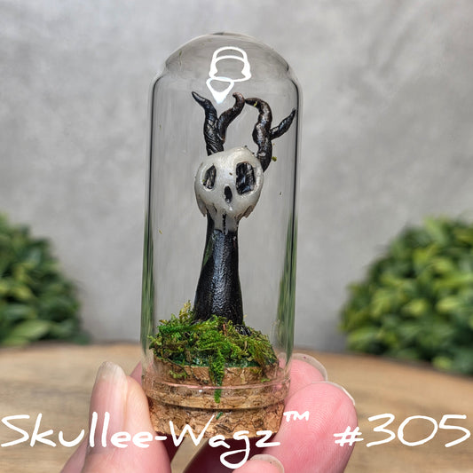 Glass dome with a skull faced creature and moss, held by a hand with a blurred green background.