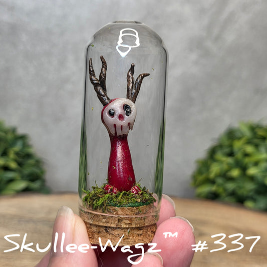 Glass dome with a skull faced creature and moss, held by a hand with a blurred green background.