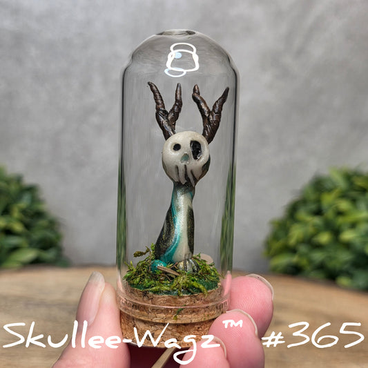 Glass dome with a skull faced creature and moss, held by a hand with a blurred green background.